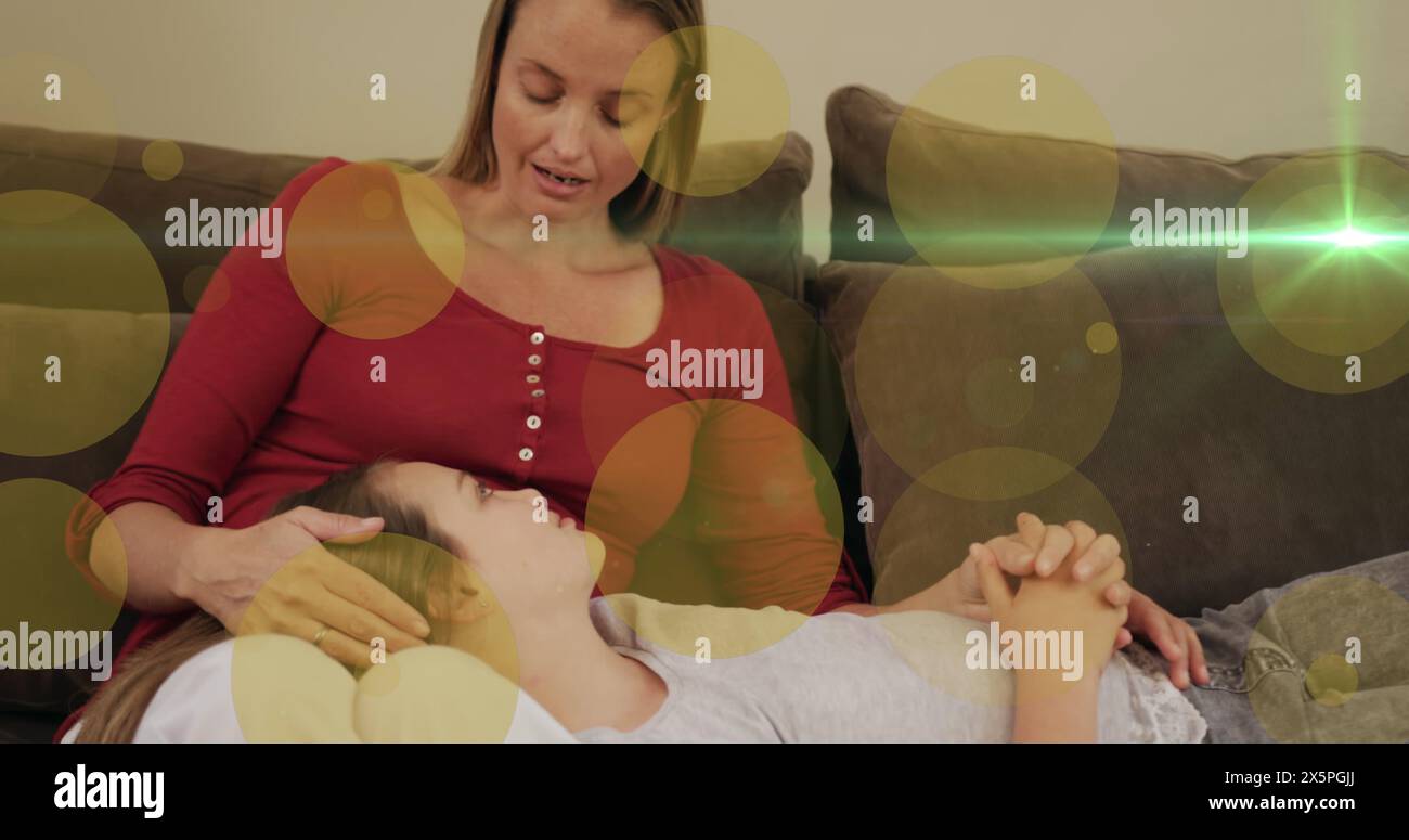 Image de lumière et de points se déplaçant sur la mère caucasienne heureuse et sa fille sur le canapé parlant Banque D'Images
