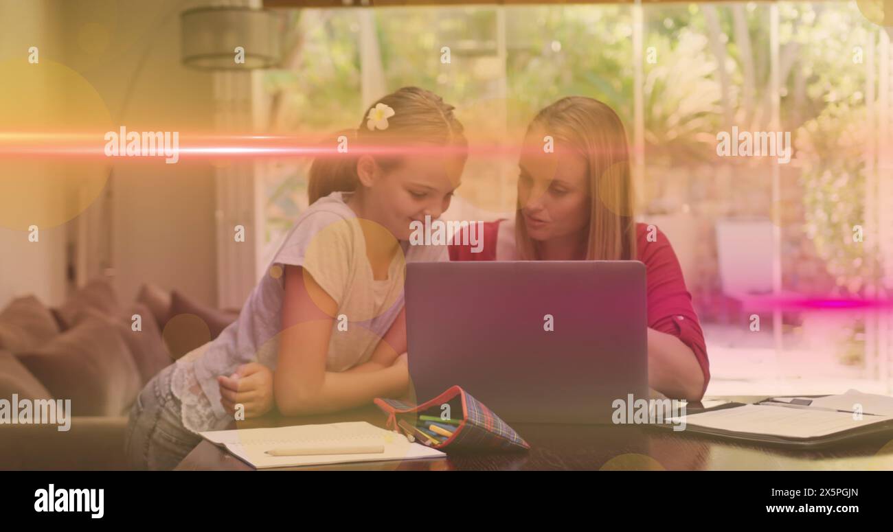 Image de la lumière se déplaçant au-dessus de la fille caucasienne heureuse et de la mère travaillant sur un ordinateur portable à la maison Banque D'Images