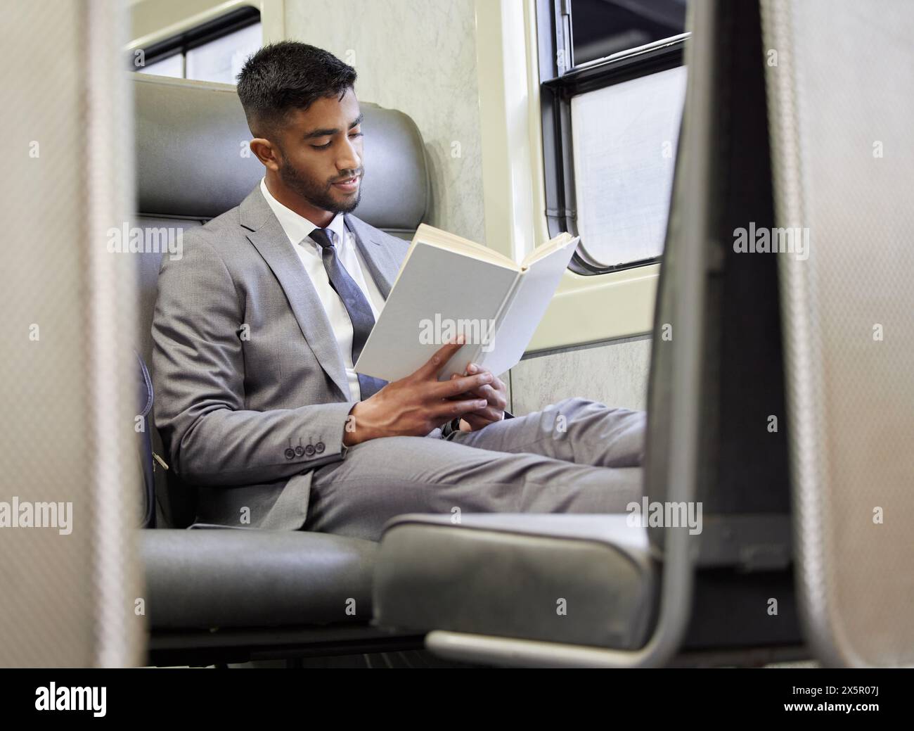 Commute, livre et homme d'affaires en train pour la lecture de la connaissance, roman de fiction et voyage du matin. Avocat indien masculin, manuel et histoire sur le métro pour Banque D'Images