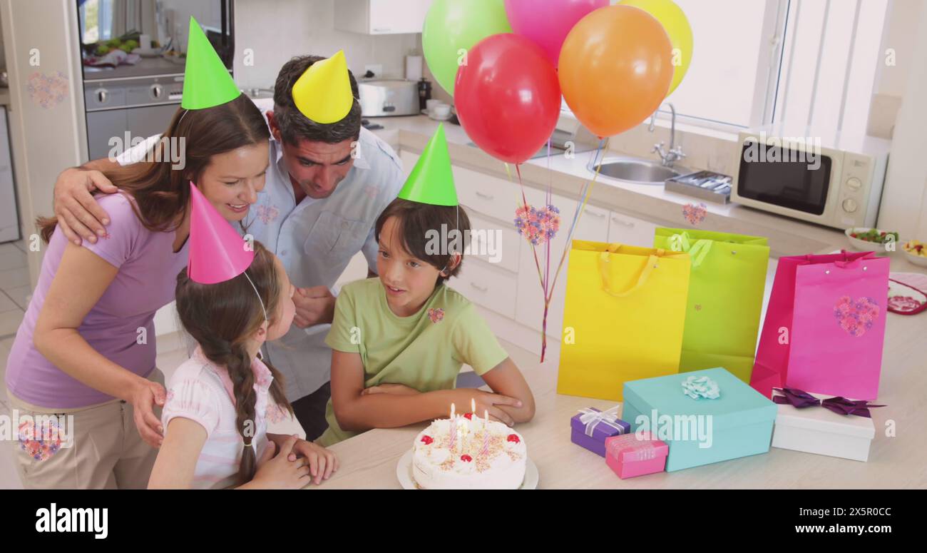 Famille caucasienne célébrant, portant des chapeaux de fête dans la cuisine Banque D'Images