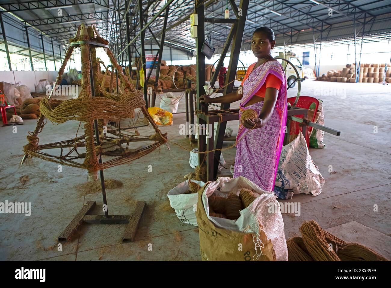 Ouvrier indien enroulant des fibres de coco dans des bobines dans le filature des ouvriers Coir Mats and Mattings Coir Mats, production de tapis de coco Banque D'Images