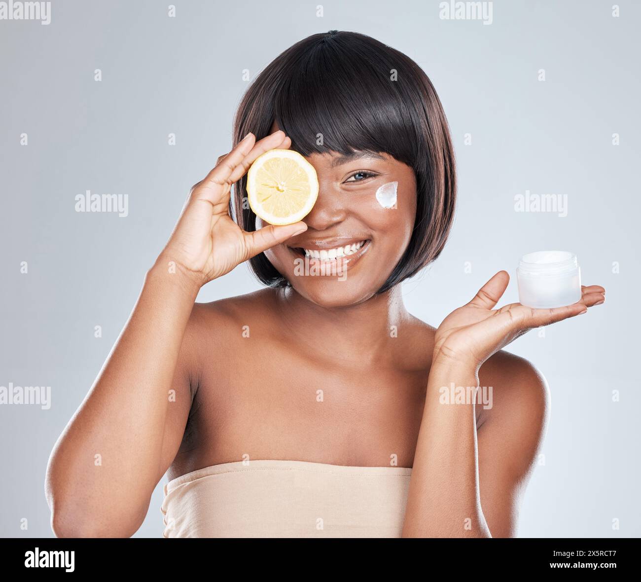 Femme heureuse, portrait et noire avec citron et récipient pour soins de la peau, crème ou crème hydratante sur un fond blanc de studio. Africain, personne féminine ou Banque D'Images