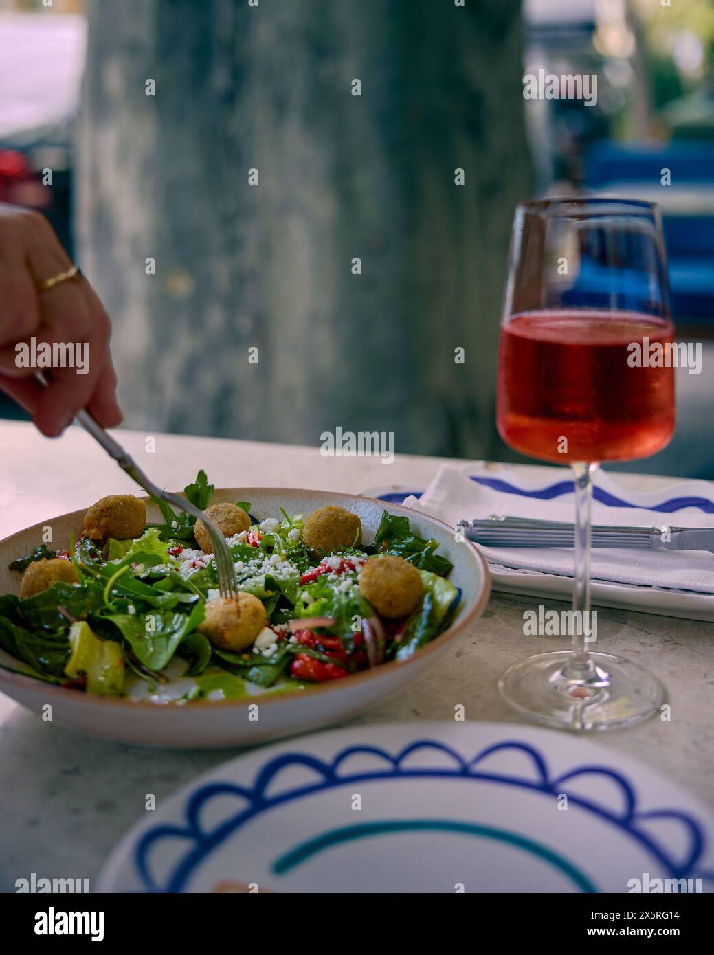 Salade avec keftedaki de veau, câpres, poivron rôti et feta grecque et verre de vin rouge sur la table du restaurant. Cuisine grecque. Banque D'Images
