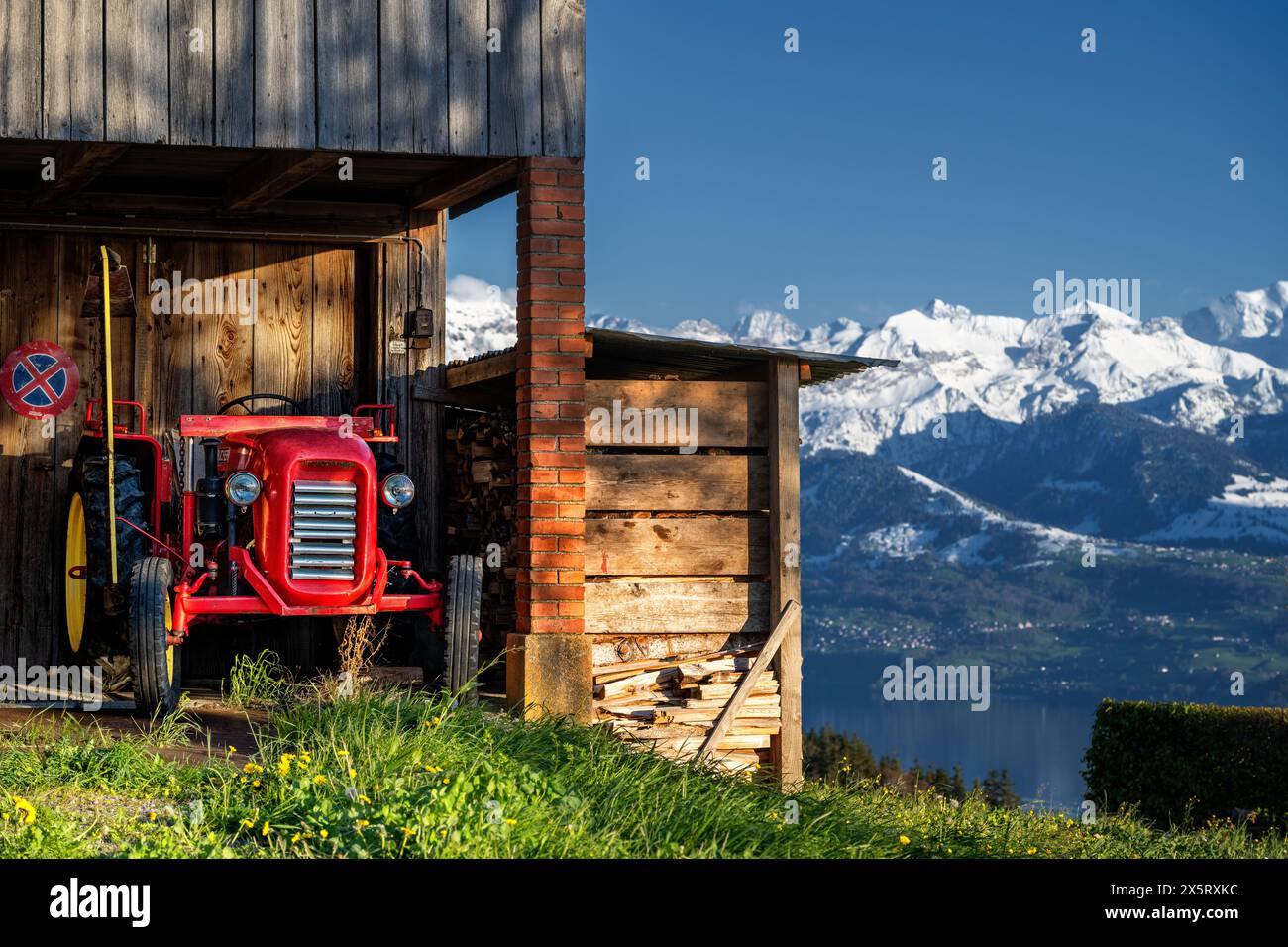 Agriculture alpine - vieux tracteur Bucher dans un abri avec des montagnes de neige dans le Banque D'Images