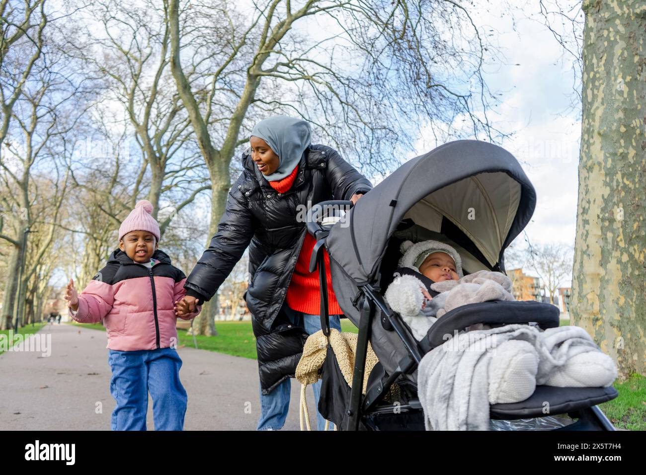 Mère marchant avec sa fille (2-3) et son bébé fils (6-11 m) dans le parc Banque D'Images