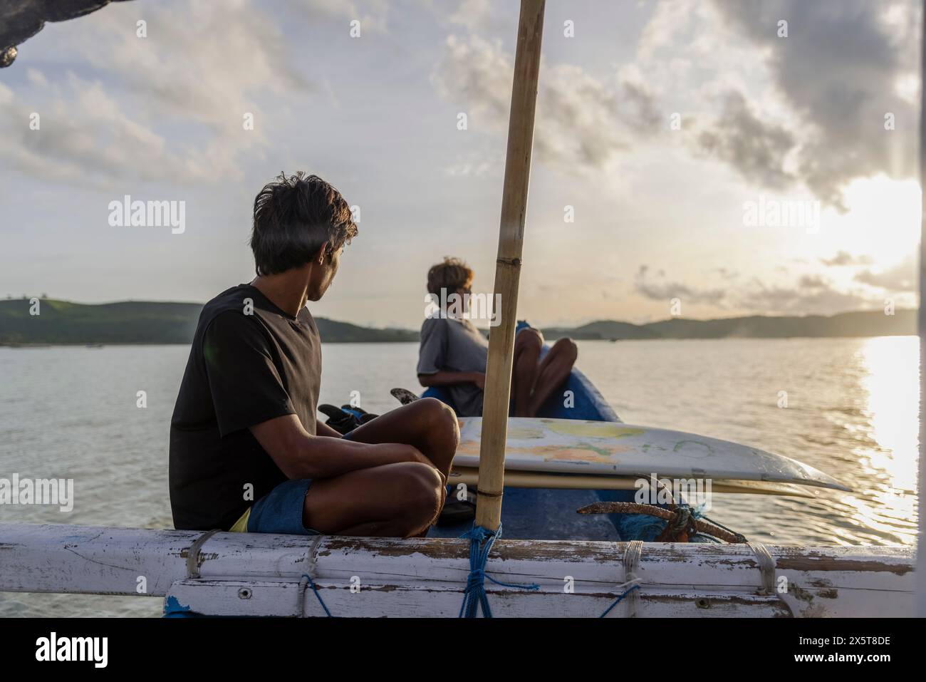 Indonésie, Lombok, Surfers regardant la vue sur la mer depuis le bateau au coucher du soleil Banque D'Images