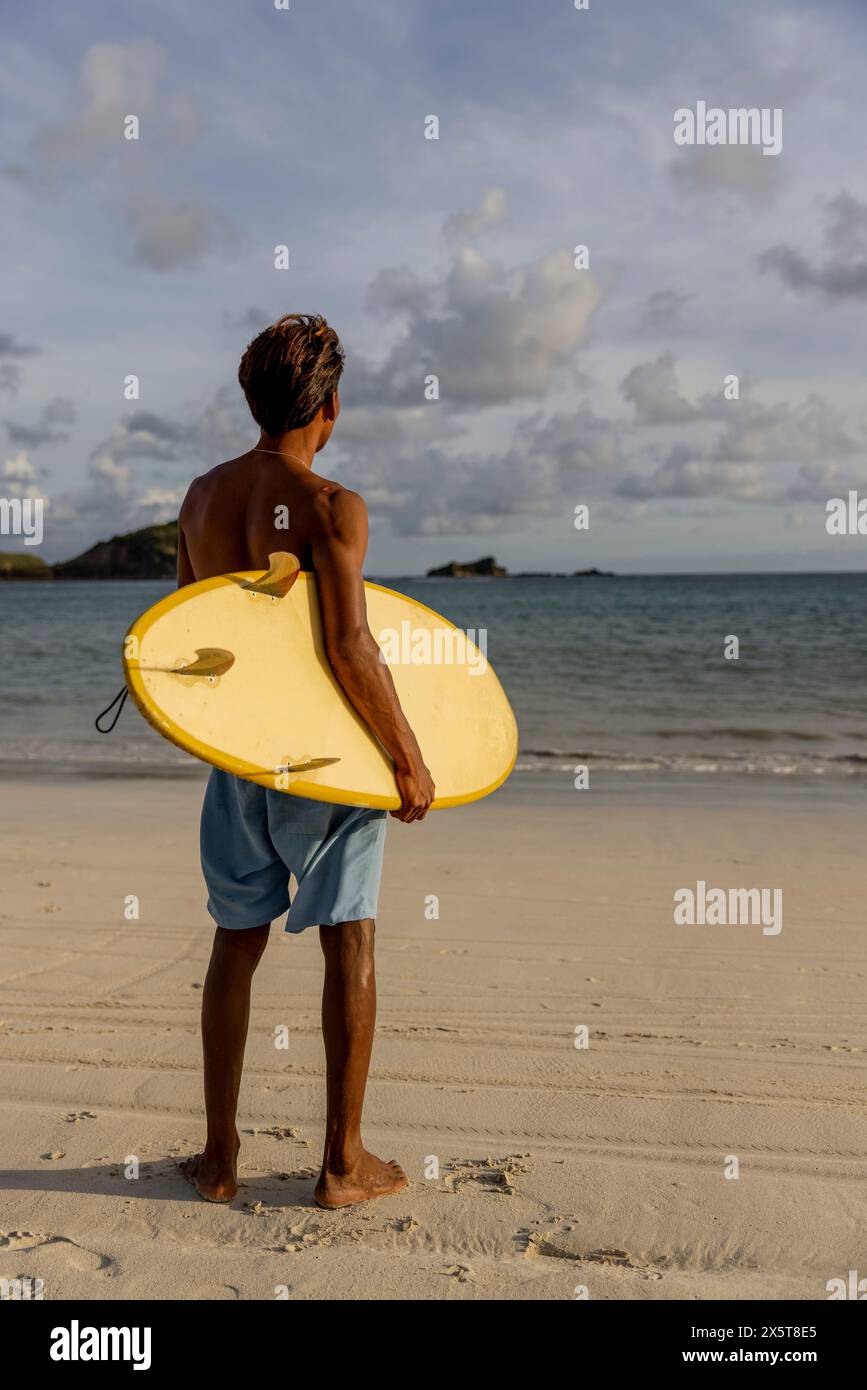 Indonésie, Lombok, surfer avec planche de surf regardant la vue sur la mer depuis la plage Banque D'Images