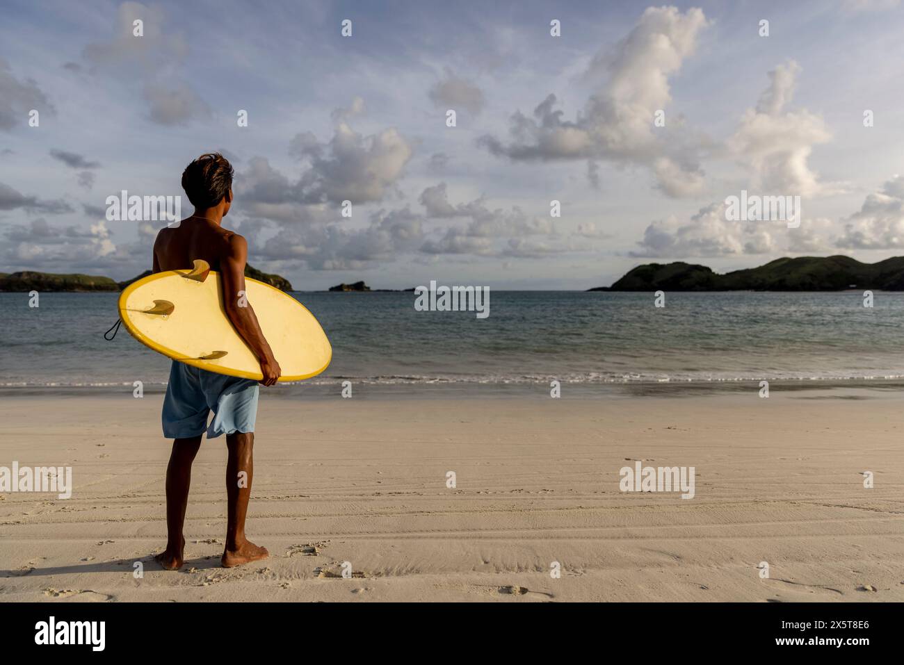 Indonésie, Lombok, surfer avec planche de surf regardant la vue sur la mer depuis la plage Banque D'Images