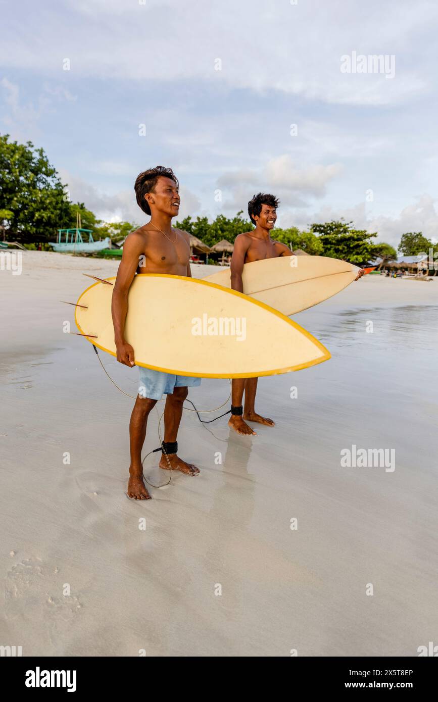 Indonésie, Lombok, Surfers regardant la mer depuis la plage Banque D'Images