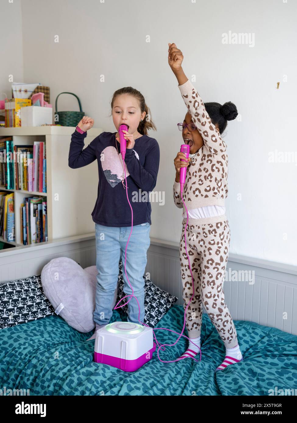 Filles amies (6-7) chantant à la maison Banque D'Images