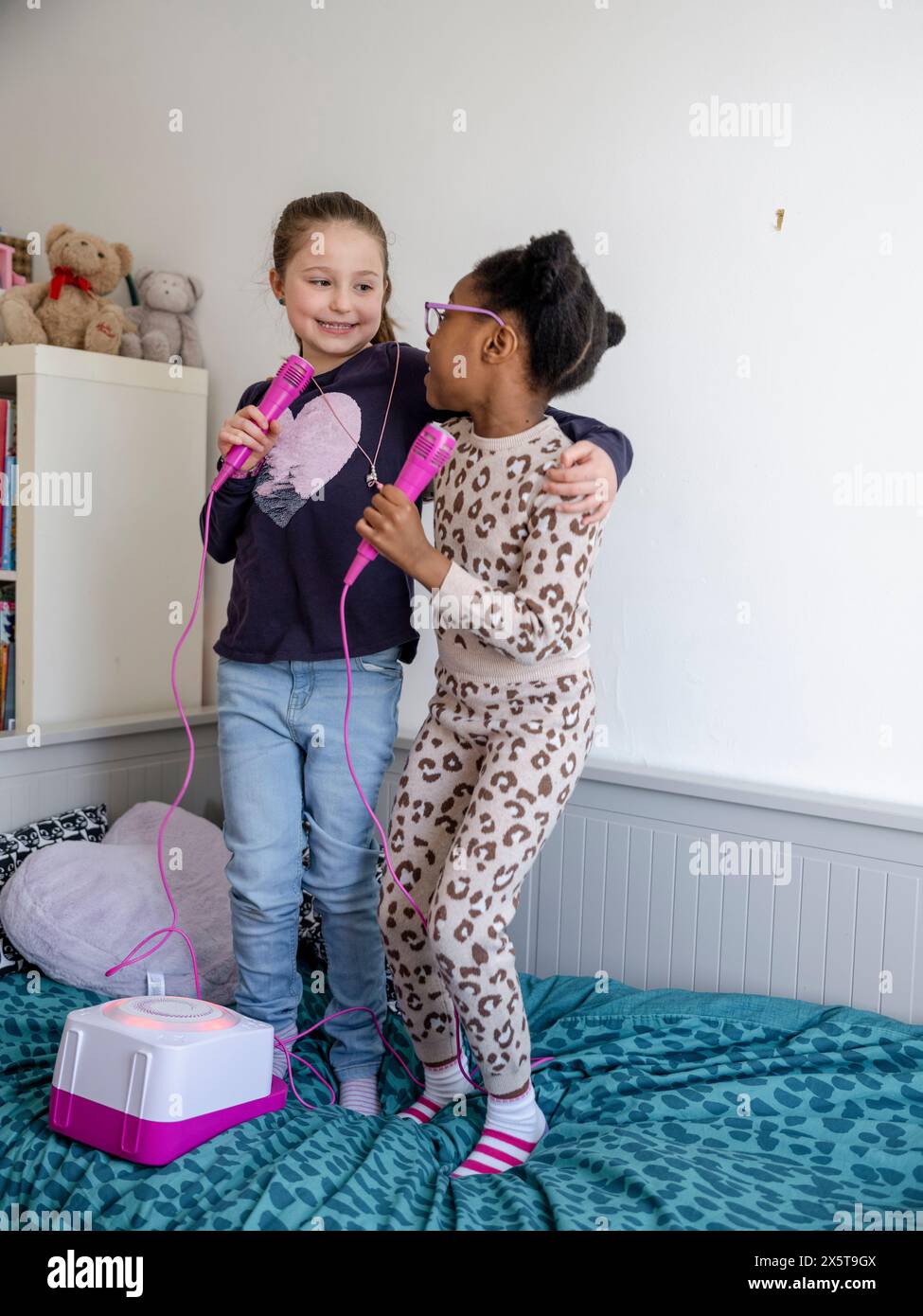 Filles amies (6-7) chantant à la maison Banque D'Images