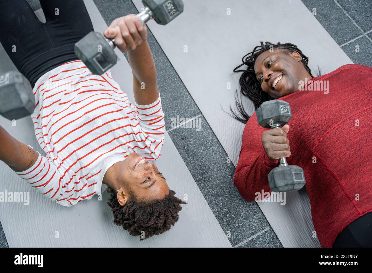 Mère et fille faisant de la musculation avec des haltères sur tapis dans le gymnase Banque D'Images