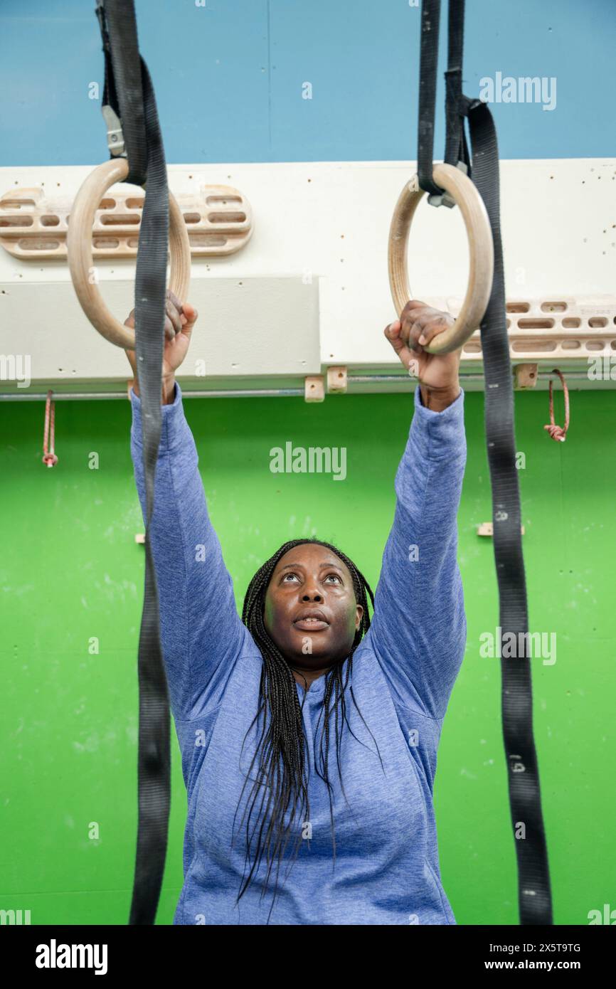 Femme exerçant sur des anneaux de gymnastique dans le gymnase Banque D'Images