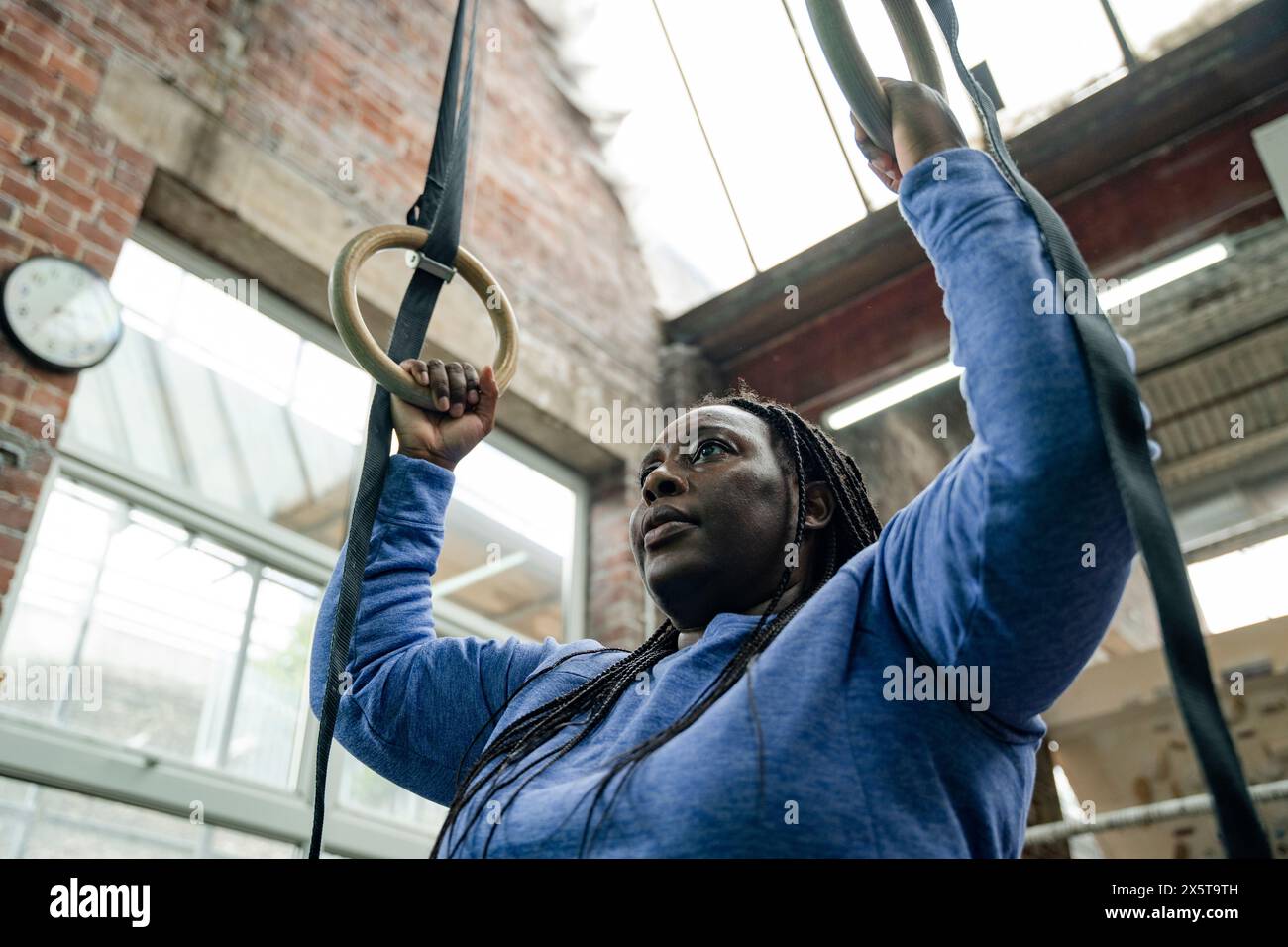 Femme exerçant sur des anneaux de gymnastique dans le gymnase Banque D'Images