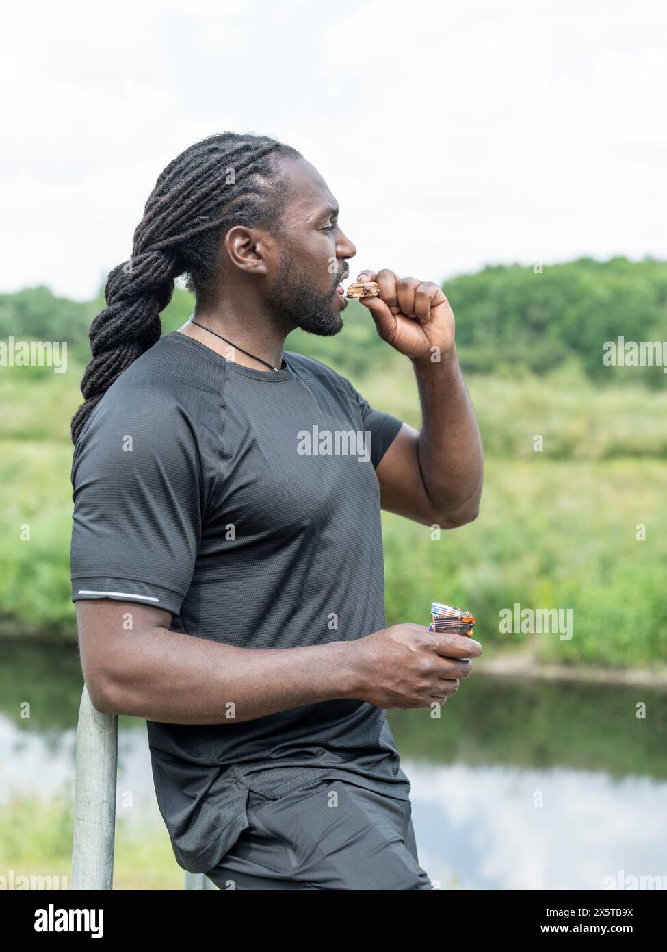 Homme mangeant barre protéinée pendant l'entraînement Banque D'Images