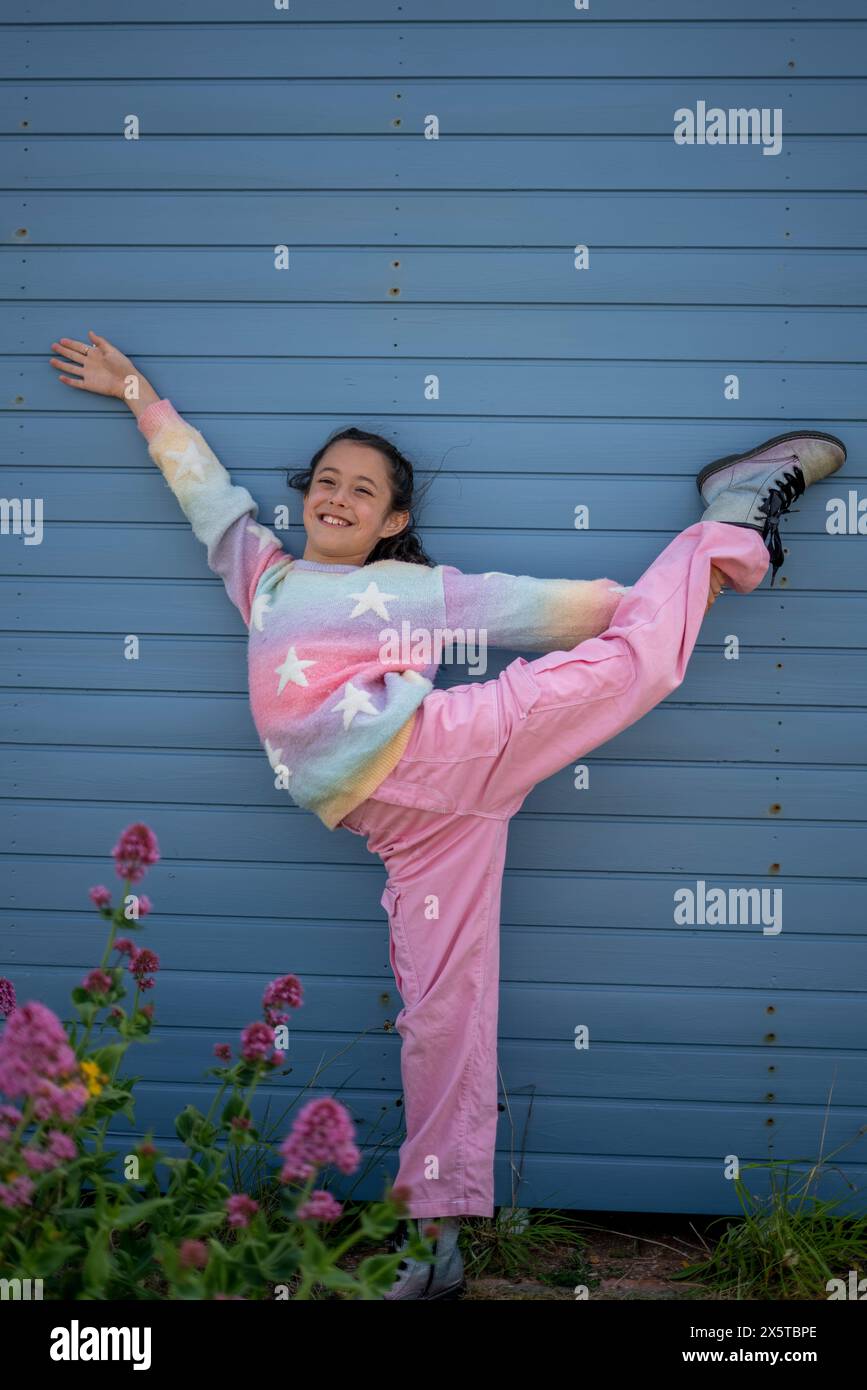 Fille souriante (8-9) debout sur une jambe à l'extérieur Banque D'Images
