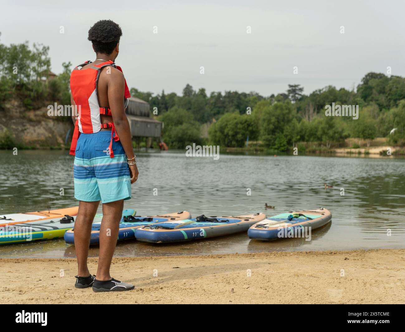 Jeune homme regardant le lac avant de paddleboard Banque D'Images