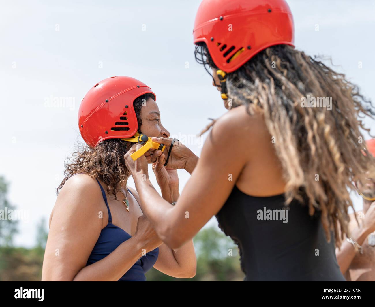 Femme aidant un ami mettant sur un casque de sport Banque D'Images