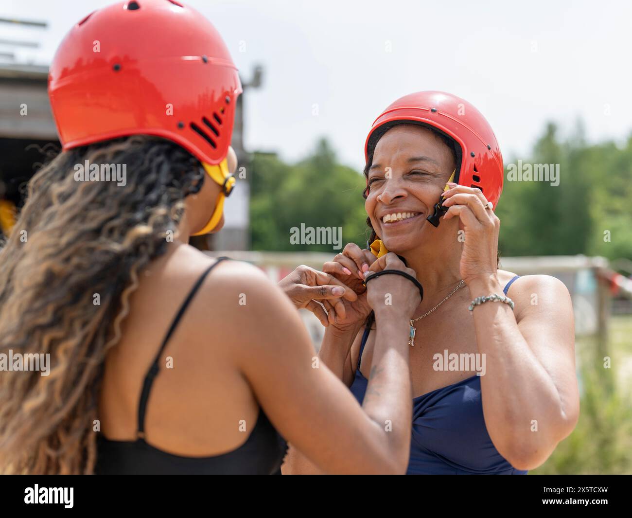 Femme aidant un ami mettant sur un casque de sport Banque D'Images
