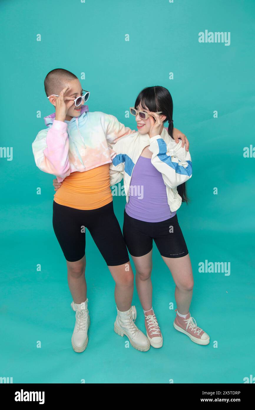 Portrait studio de deux filles souriantes portant des lunettes de soleil Banque D'Images