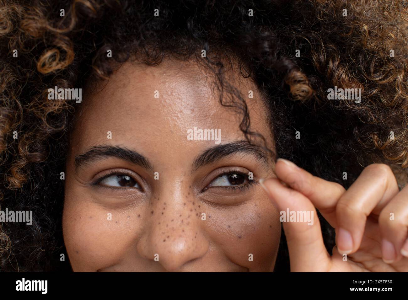 Femme brune touchant une mèche de cheveux bouclés Banque D'Images
