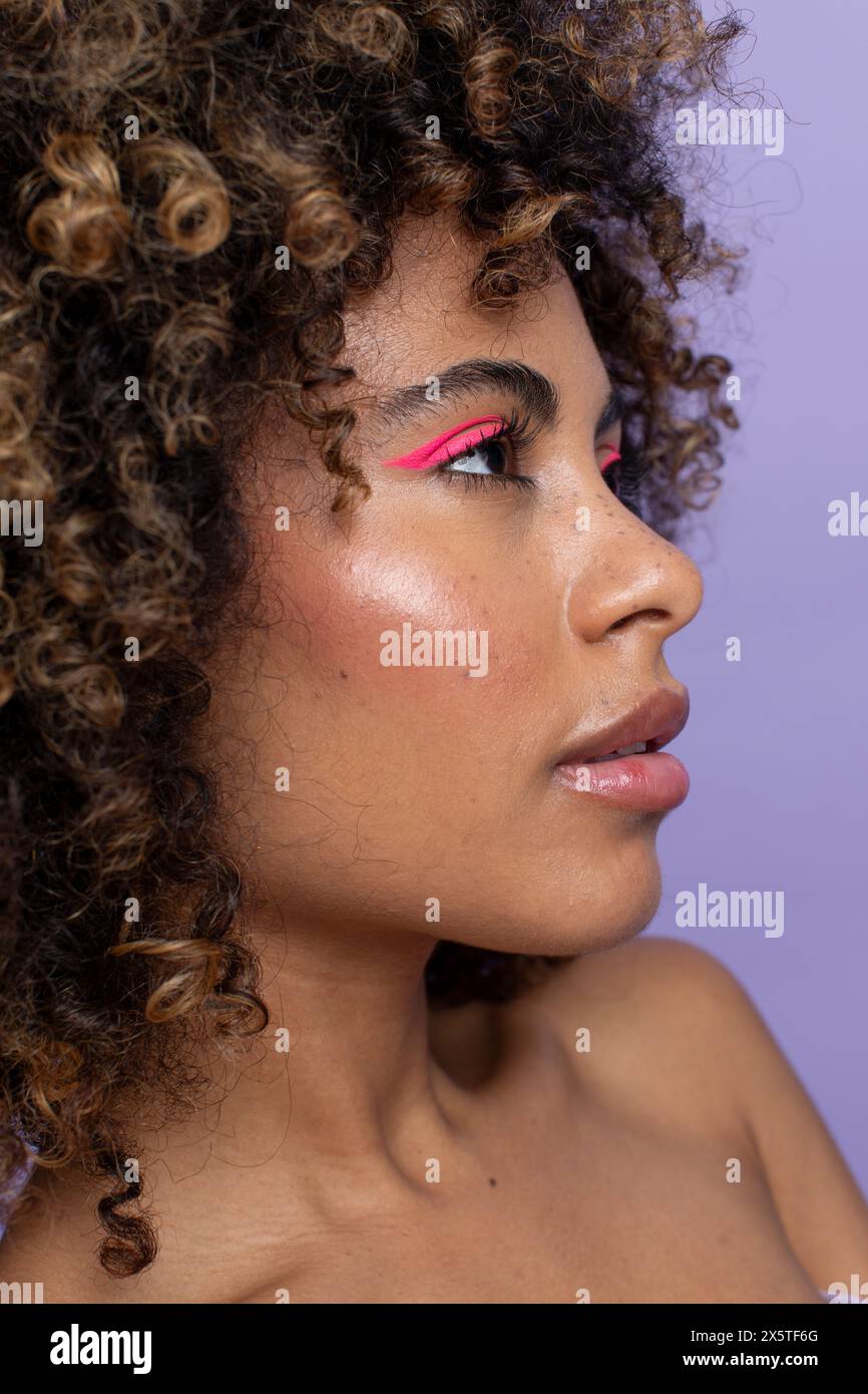 Vue de côté de la femme avec les cheveux bouclés et le maquillage rose Banque D'Images