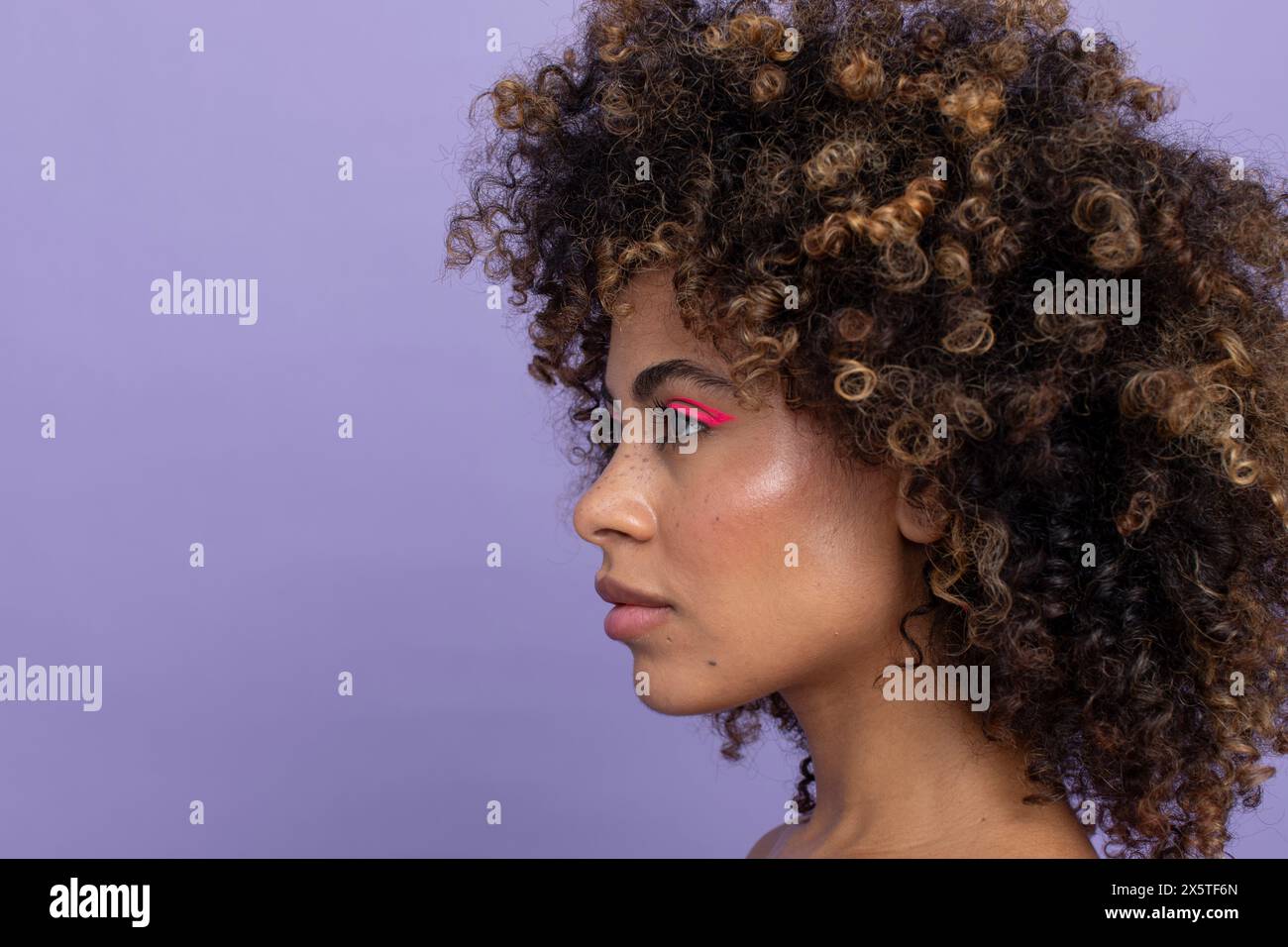 Vue de côté de la femme avec les cheveux bouclés et le maquillage rose Banque D'Images