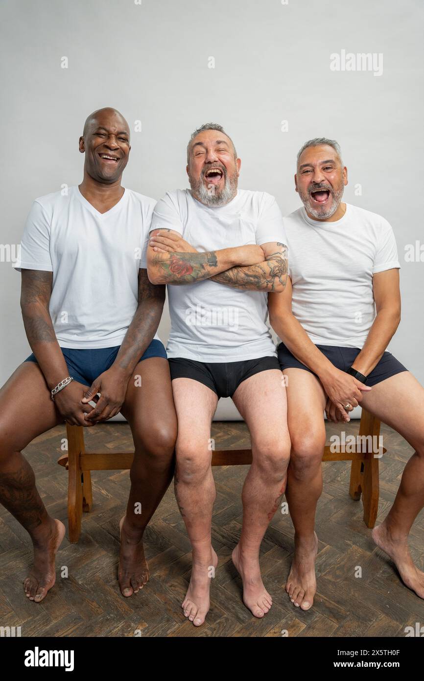 Portrait d'hommes seniors souriants en t-shirts blancs sur fond gris Banque D'Images