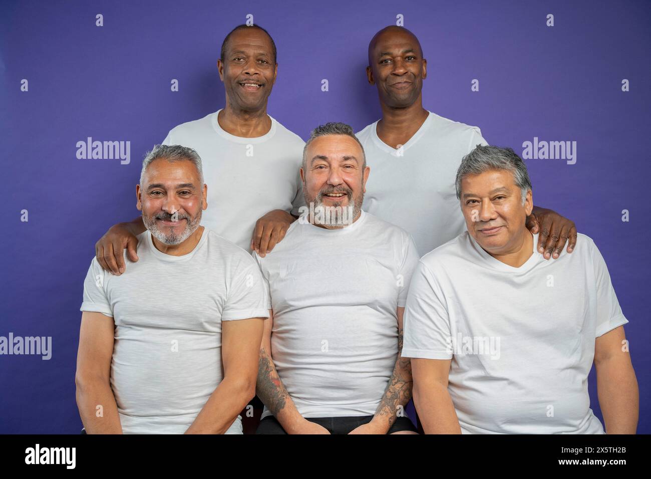 Portrait d'hommes seniors souriants sur fond violet Banque D'Images