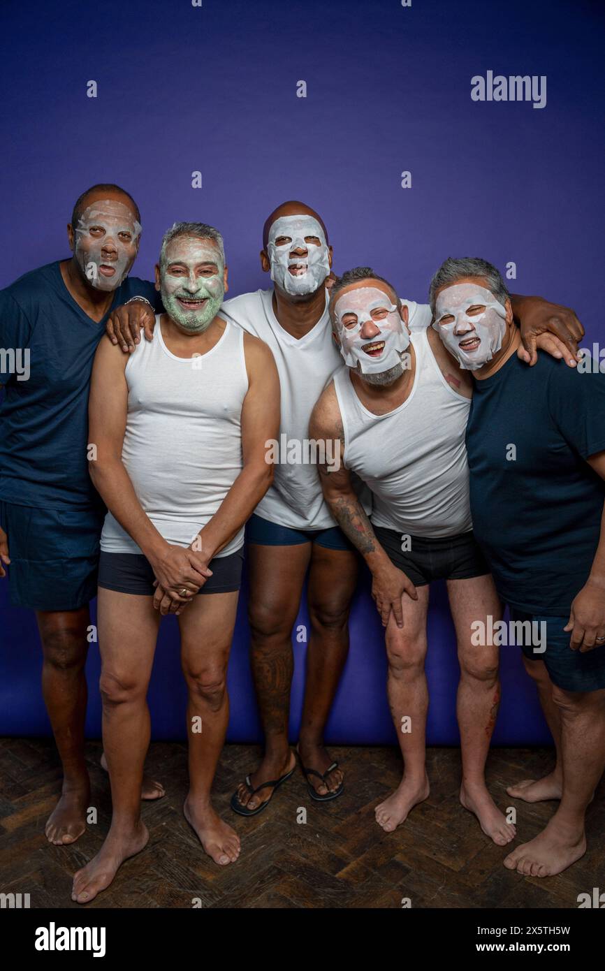 Portrait d'hommes avec des masques faciaux sur fond violet Banque D'Images