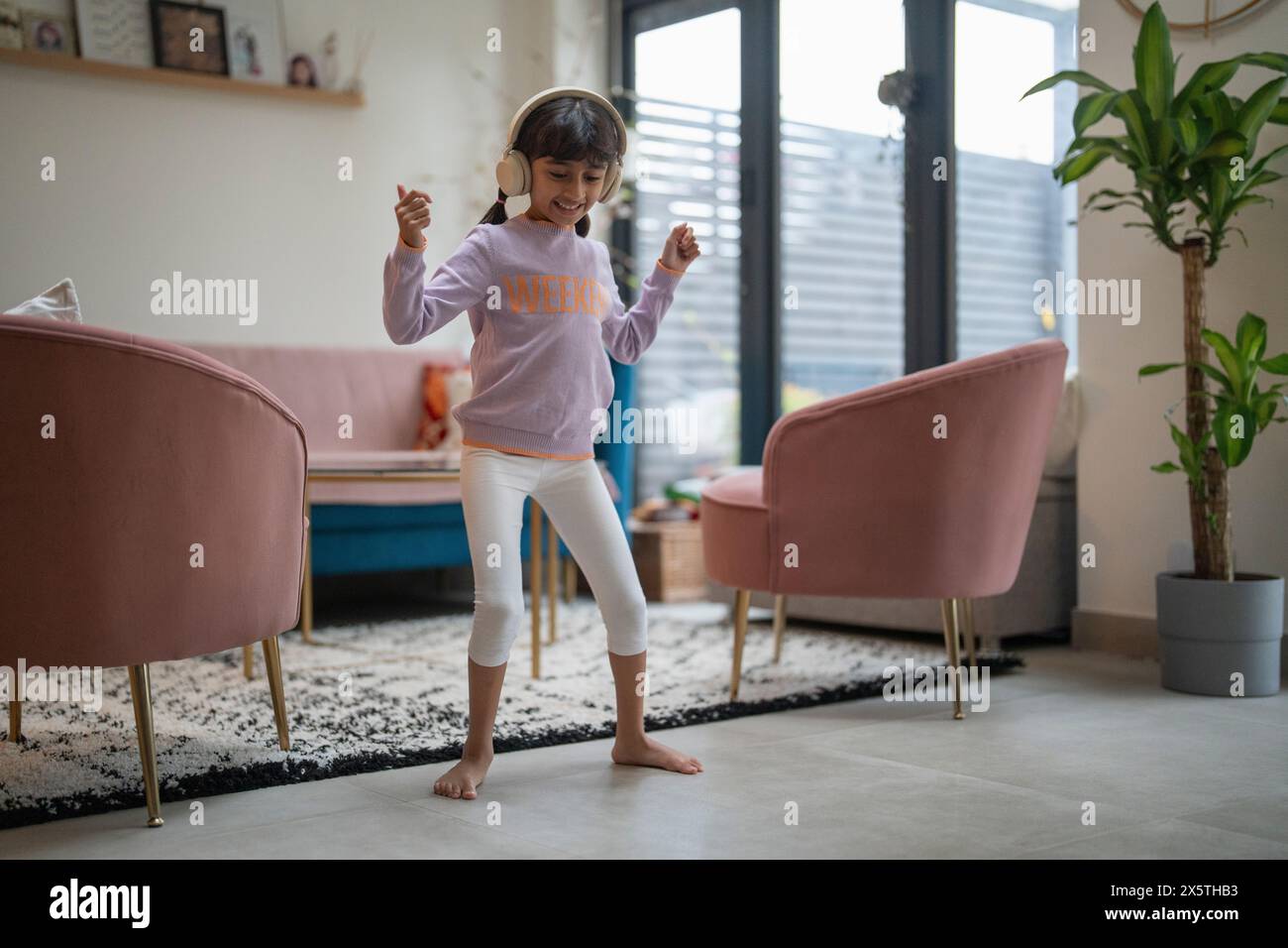 Petite fille dansant avec des écouteurs dans le salon Banque D'Images