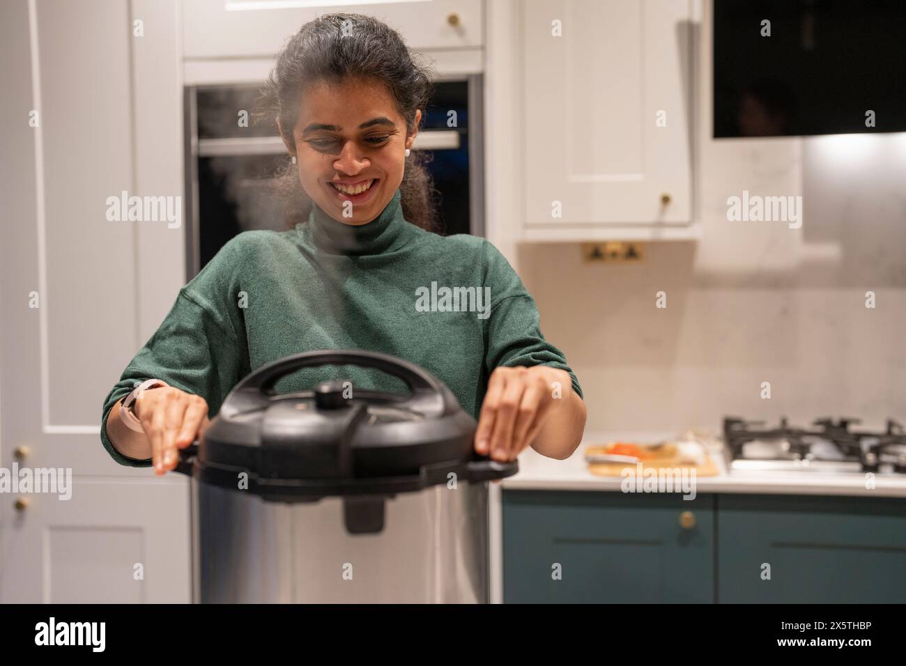 Femme ouvrant le pot d'autocuiseur dans la cuisine Banque D'Images