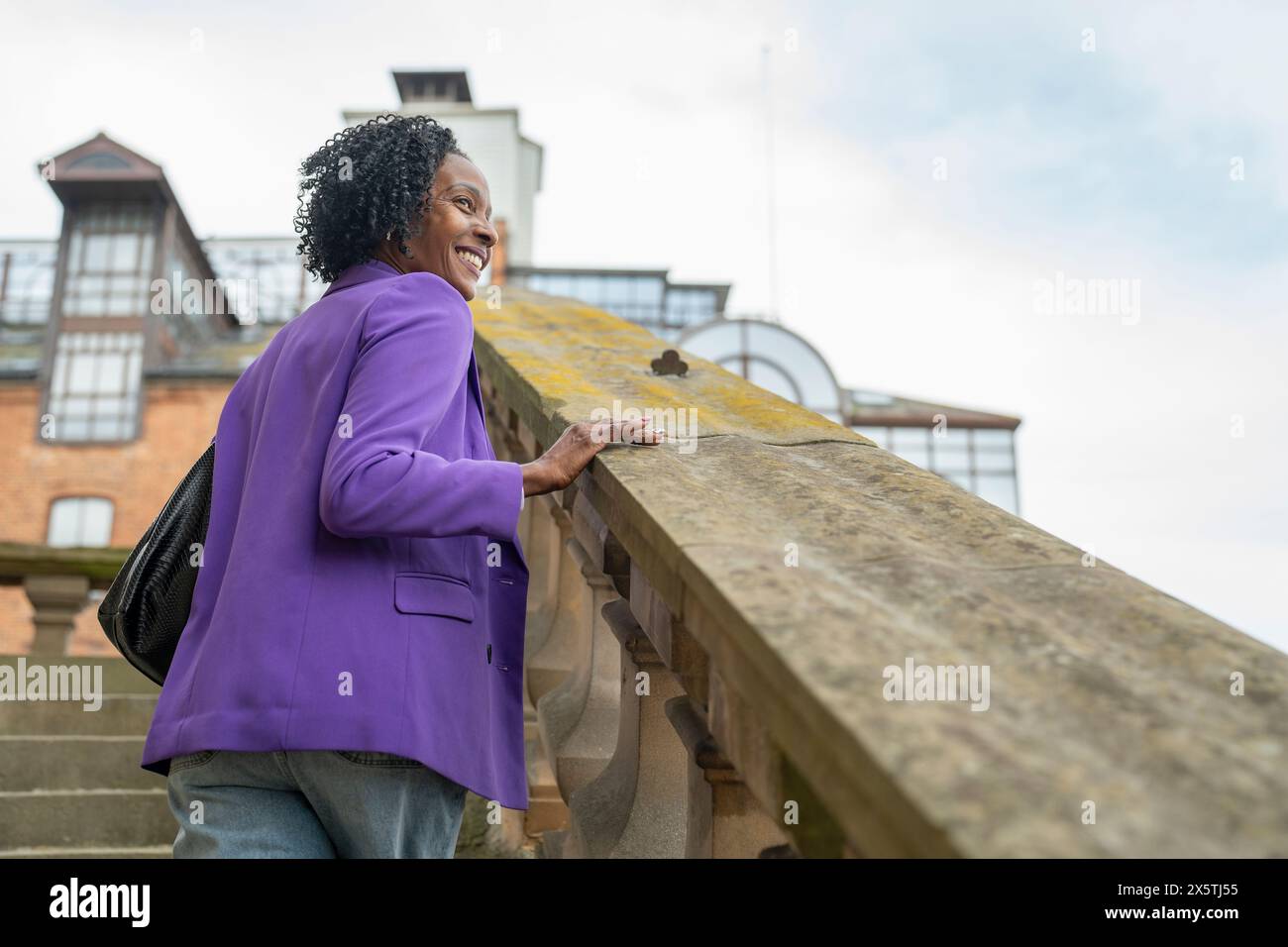Vue arrière d'une femme souriante marchant sur des marches et regardant la vue Banque D'Images