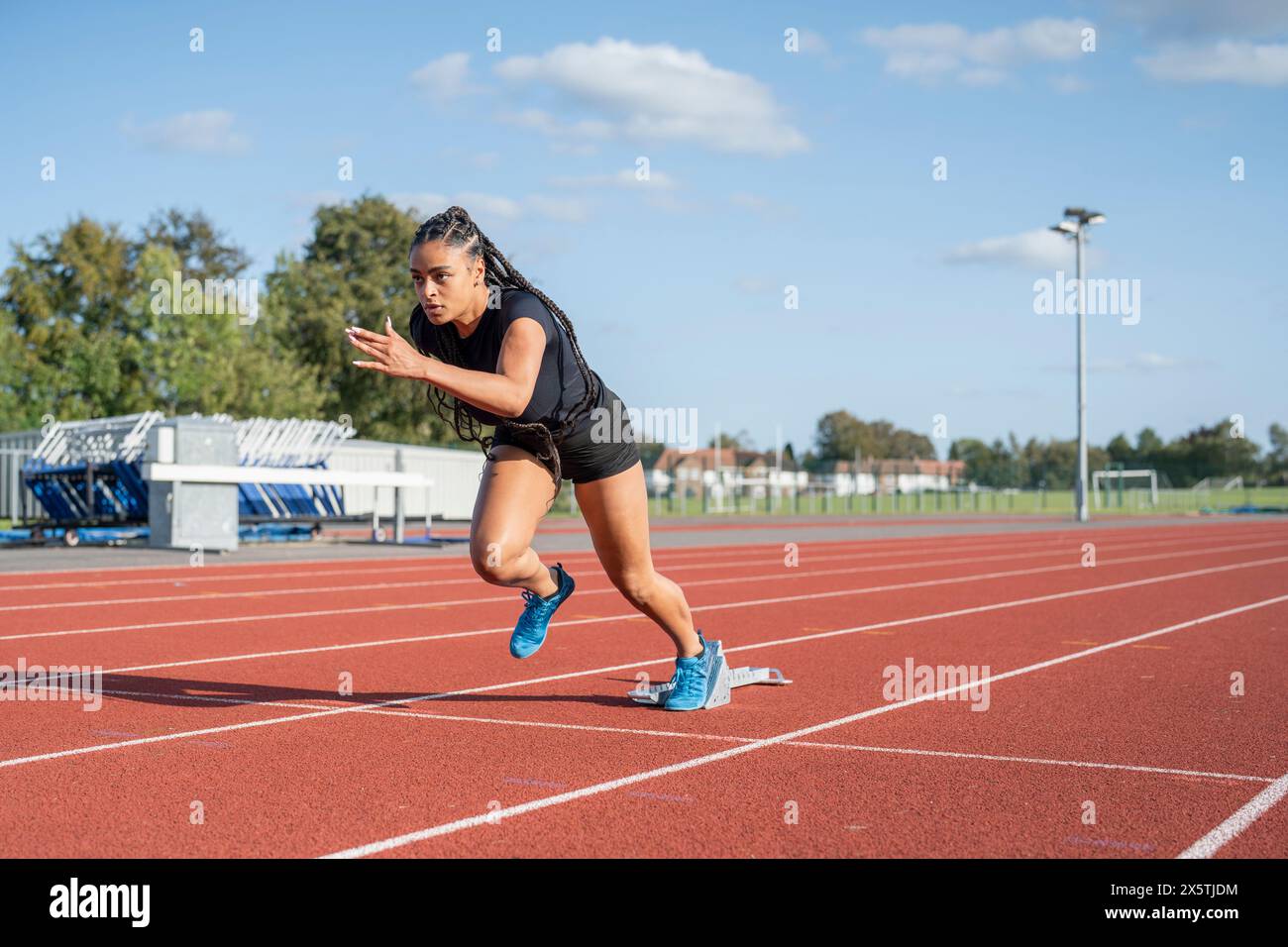 Athlète féminine qui court sur la ligne de départ au stade Banque D'Images