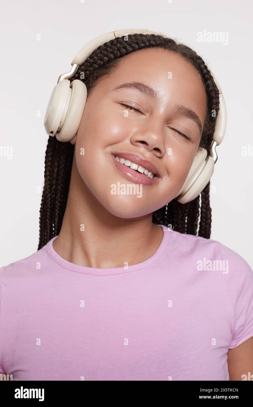 Portrait studio de fille souriante avec écouteurs et yeux fermés Banque D'Images