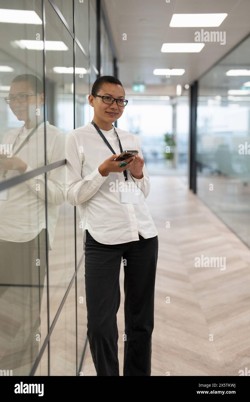 Employé de bureau non binaire debout dans le couloir Banque D'Images