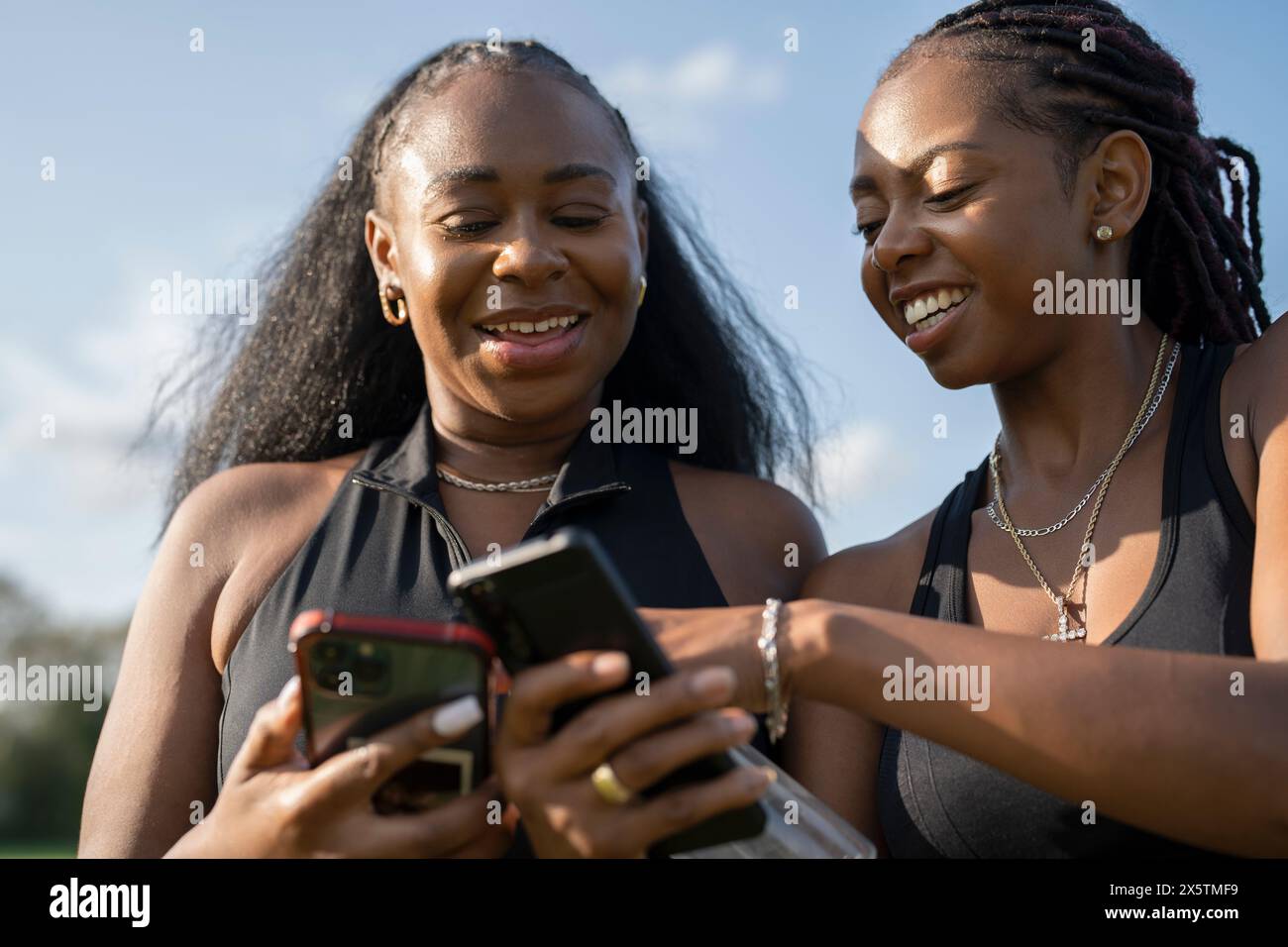 Amies féminines souriantes à l'aide de téléphones intelligents Banque D'Images