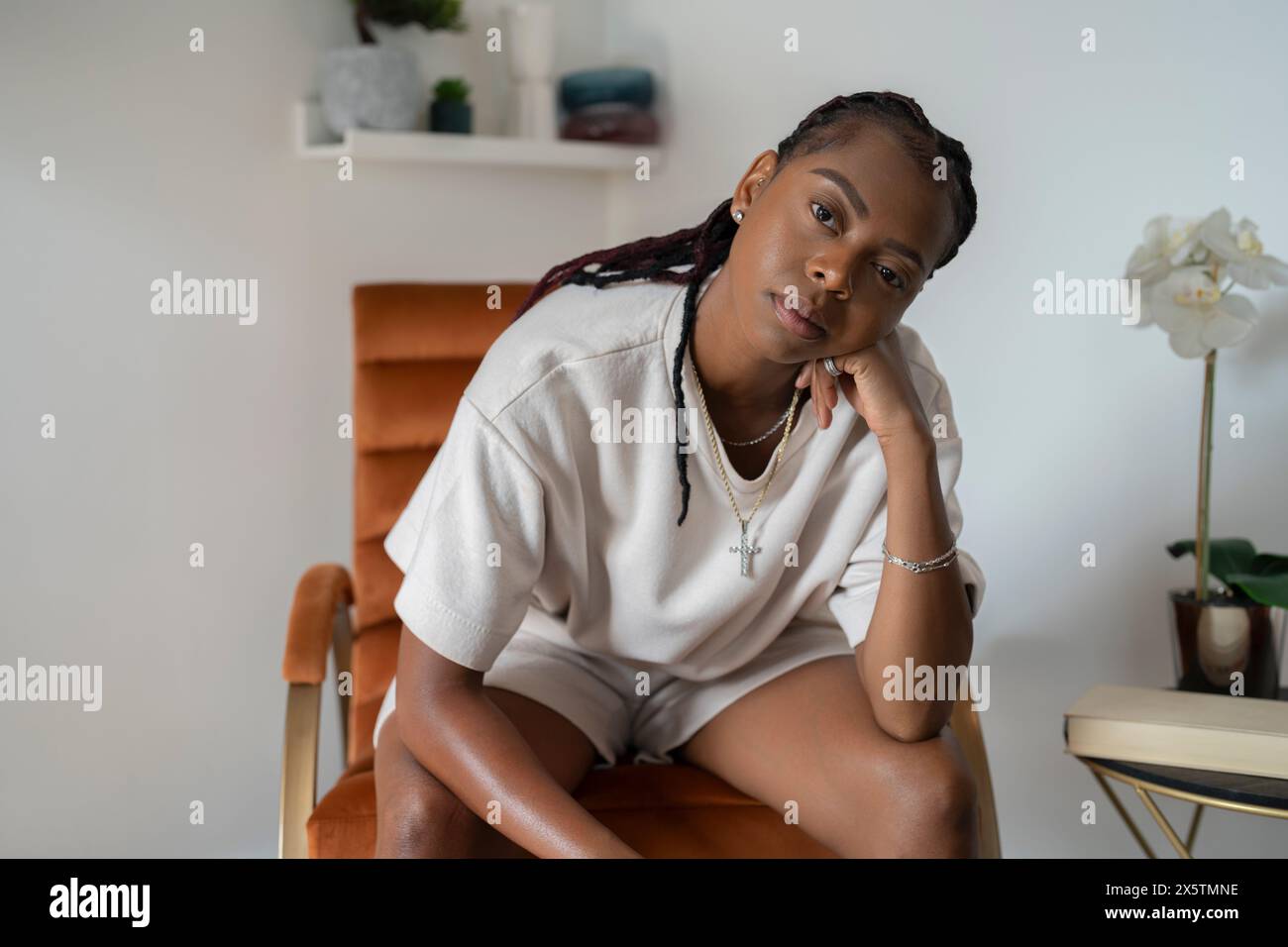 Portrait de belle femme regardant la caméra tout en étant assis dans un fauteuil à la maison Banque D'Images