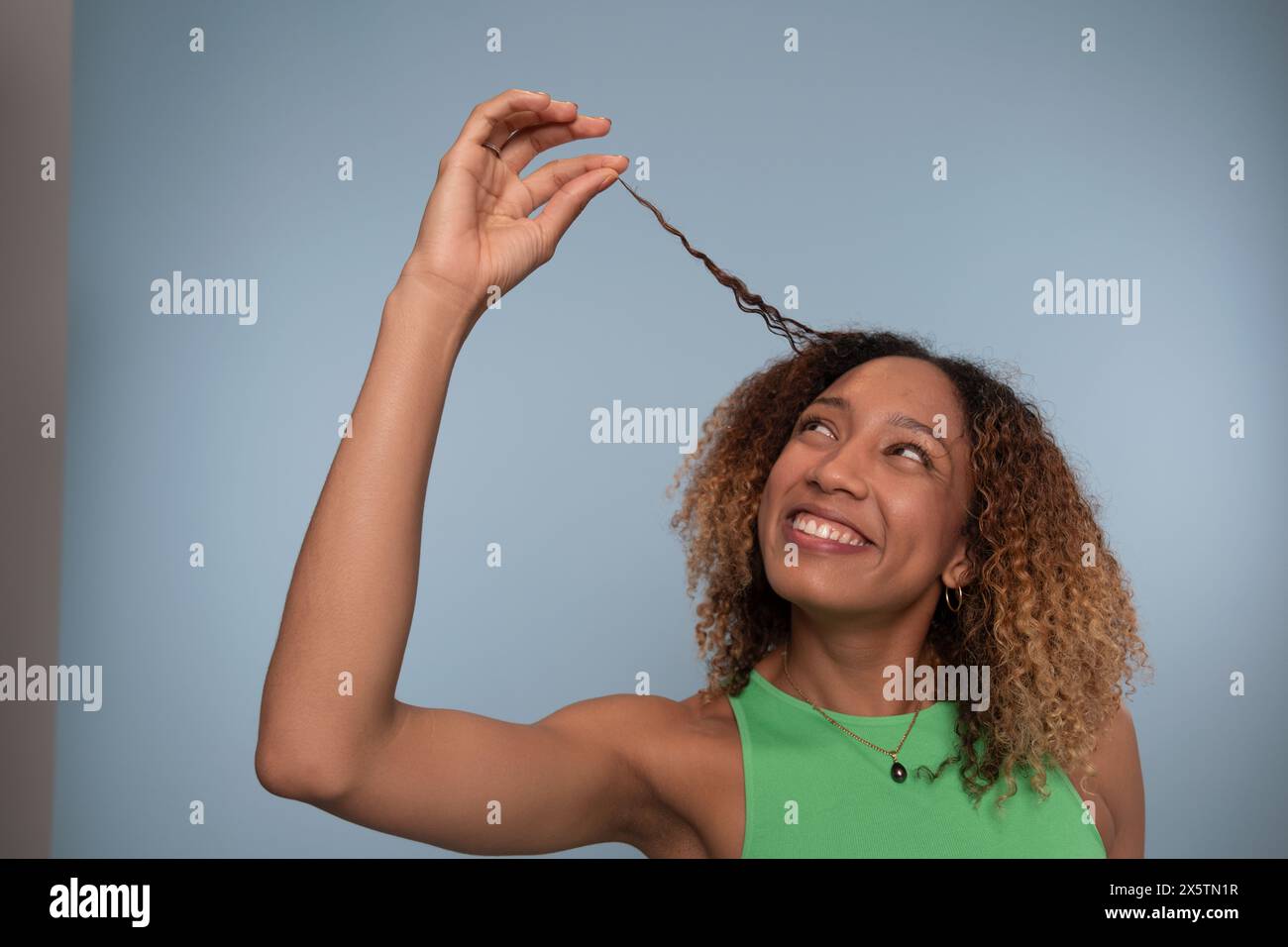 Femme levant la tête et tenant les cheveux bouclés Banque D'Images