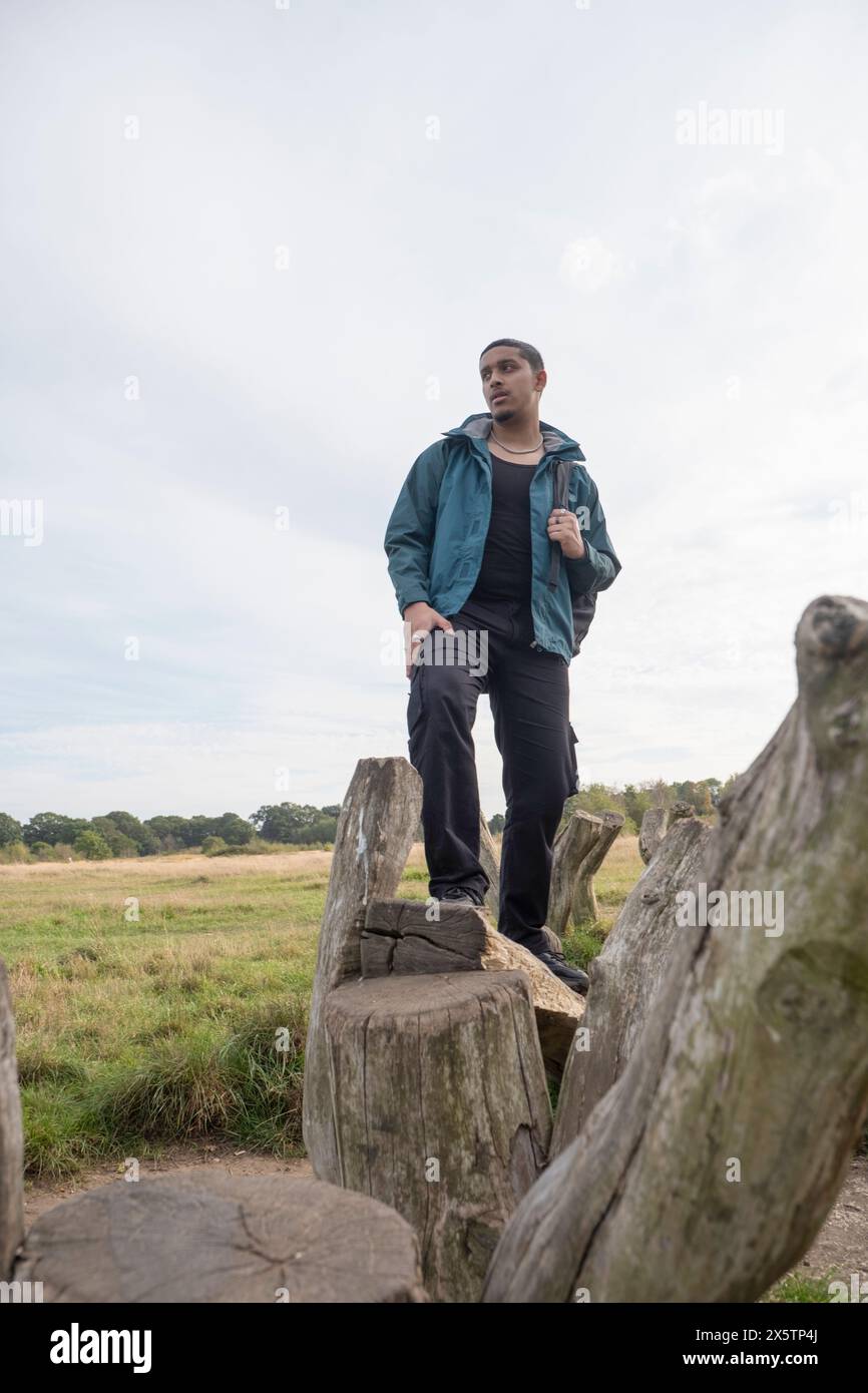 Portrait d'homme avec sac à dos debout sur de vieux poteaux en bois Banque D'Images