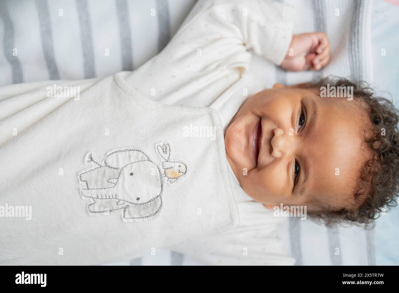 Petite fille souriante avec les cheveux bouclés et les yeux bruns Banque D'Images