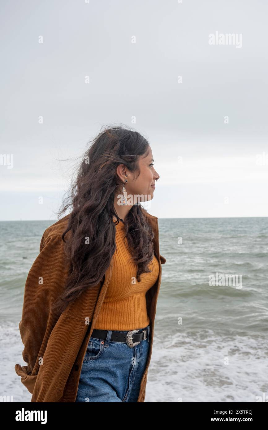 Femme réfléchie regardant la mer un jour nuageux Banque D'Images