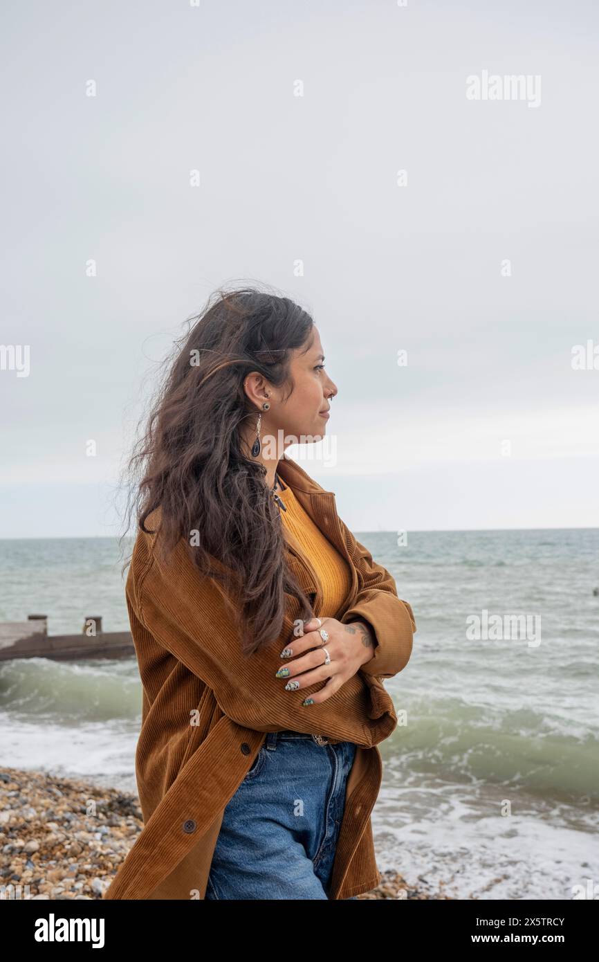 Femme réfléchie regardant la mer un jour nuageux Banque D'Images