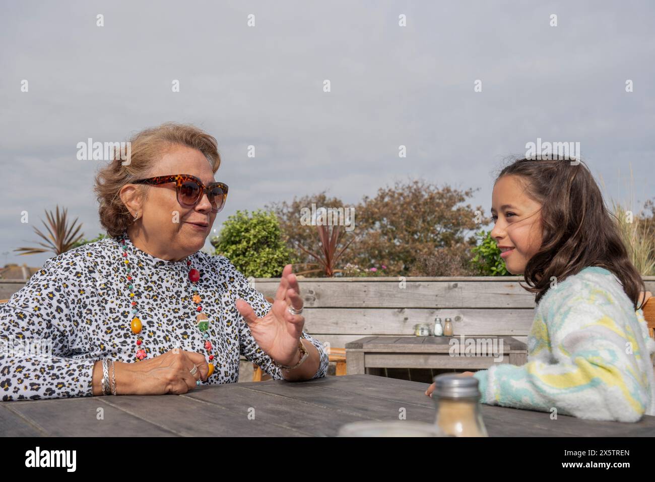 Grand-mère et petite-fille parlant tout en étant assis dans le restaurant en plein air Banque D'Images