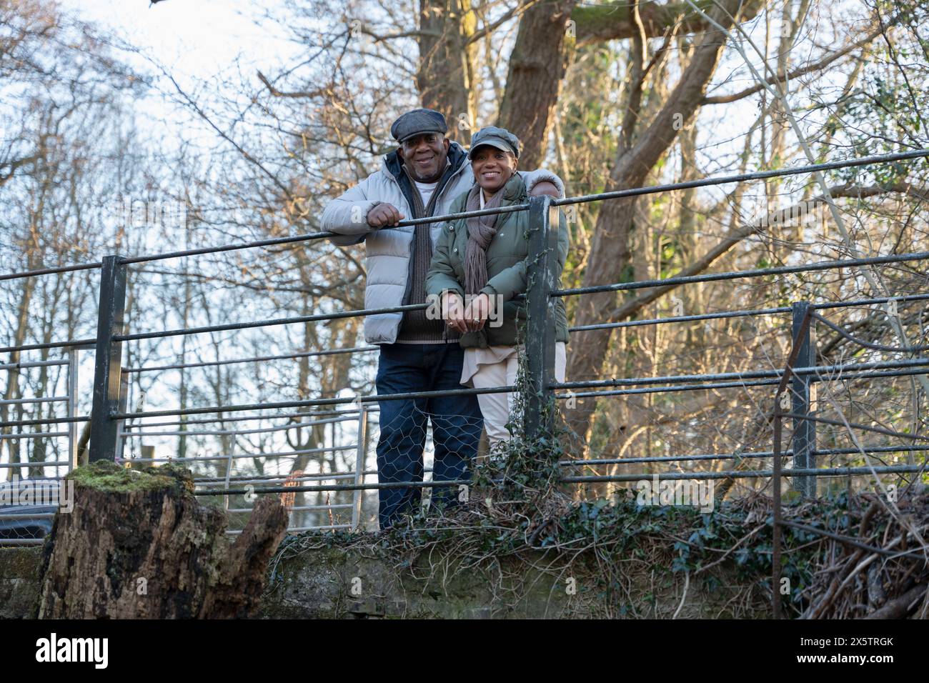 Couple senior debout près de la clôture, regardant la caméra Banque D'Images
