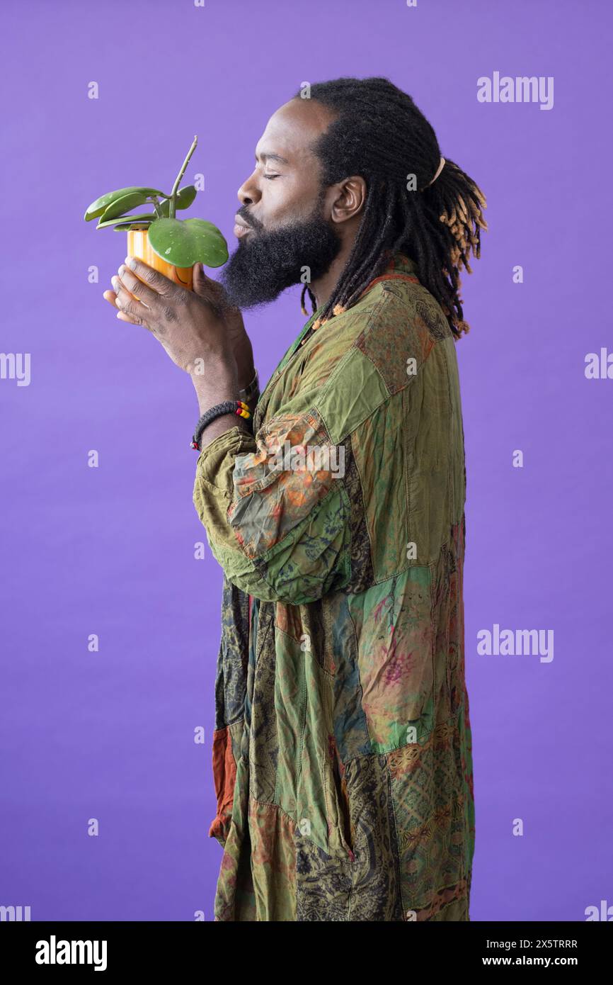 Vue latérale de l'homme avec les yeux fermés tenant la plante en pot Banque D'Images