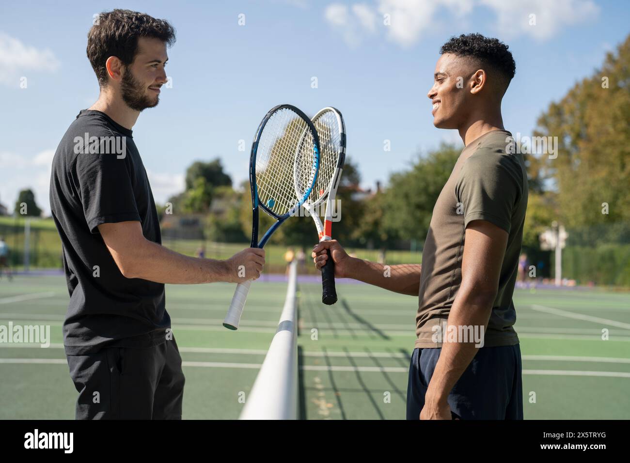 Deux hommes souriants dans le court de tennis Banque D'Images
