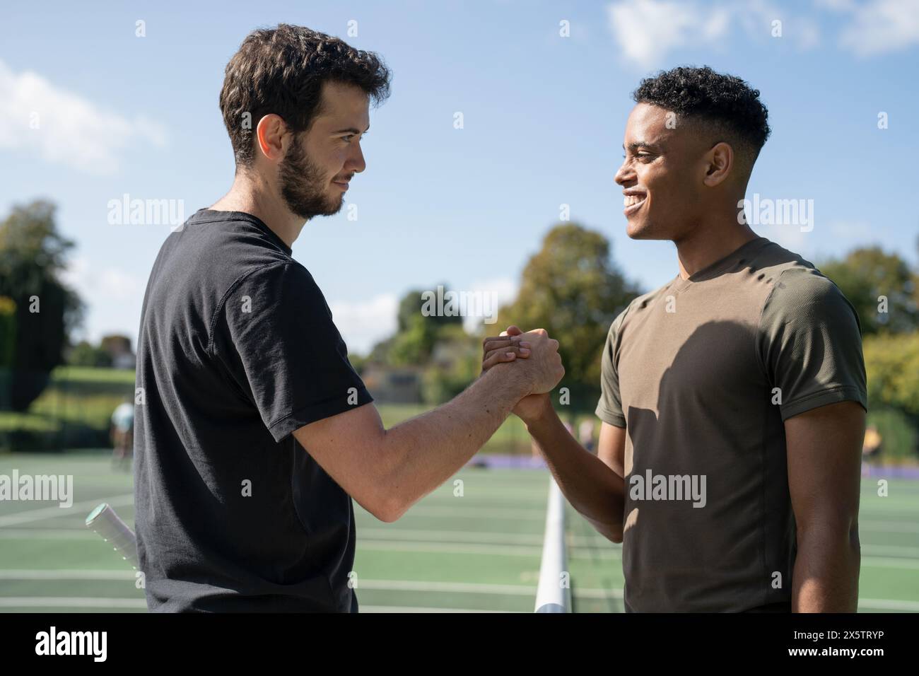 Deux hommes se serrant la main dans le court de tennis Banque D'Images