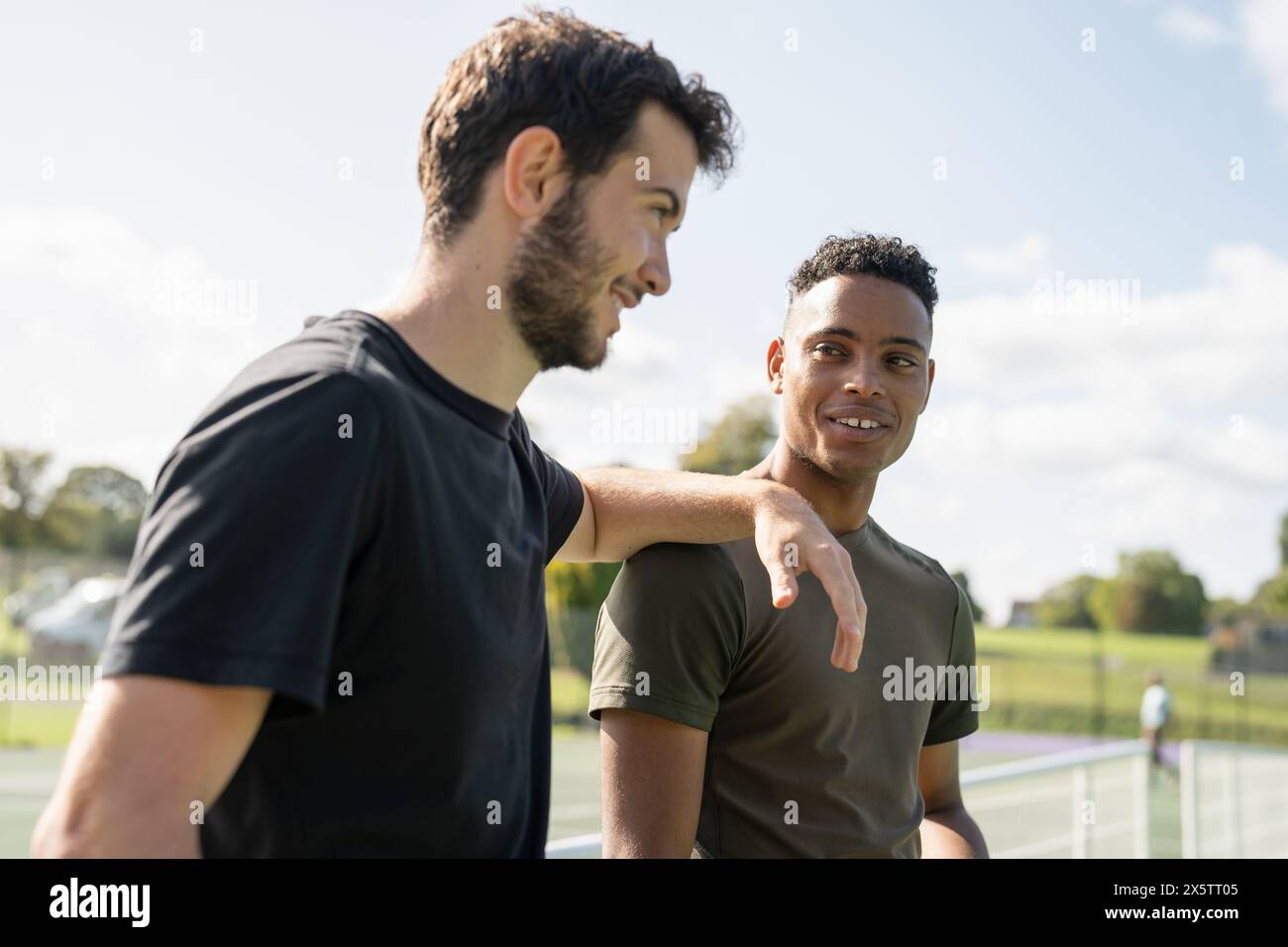 Deux hommes souriants dans le court de tennis Banque D'Images