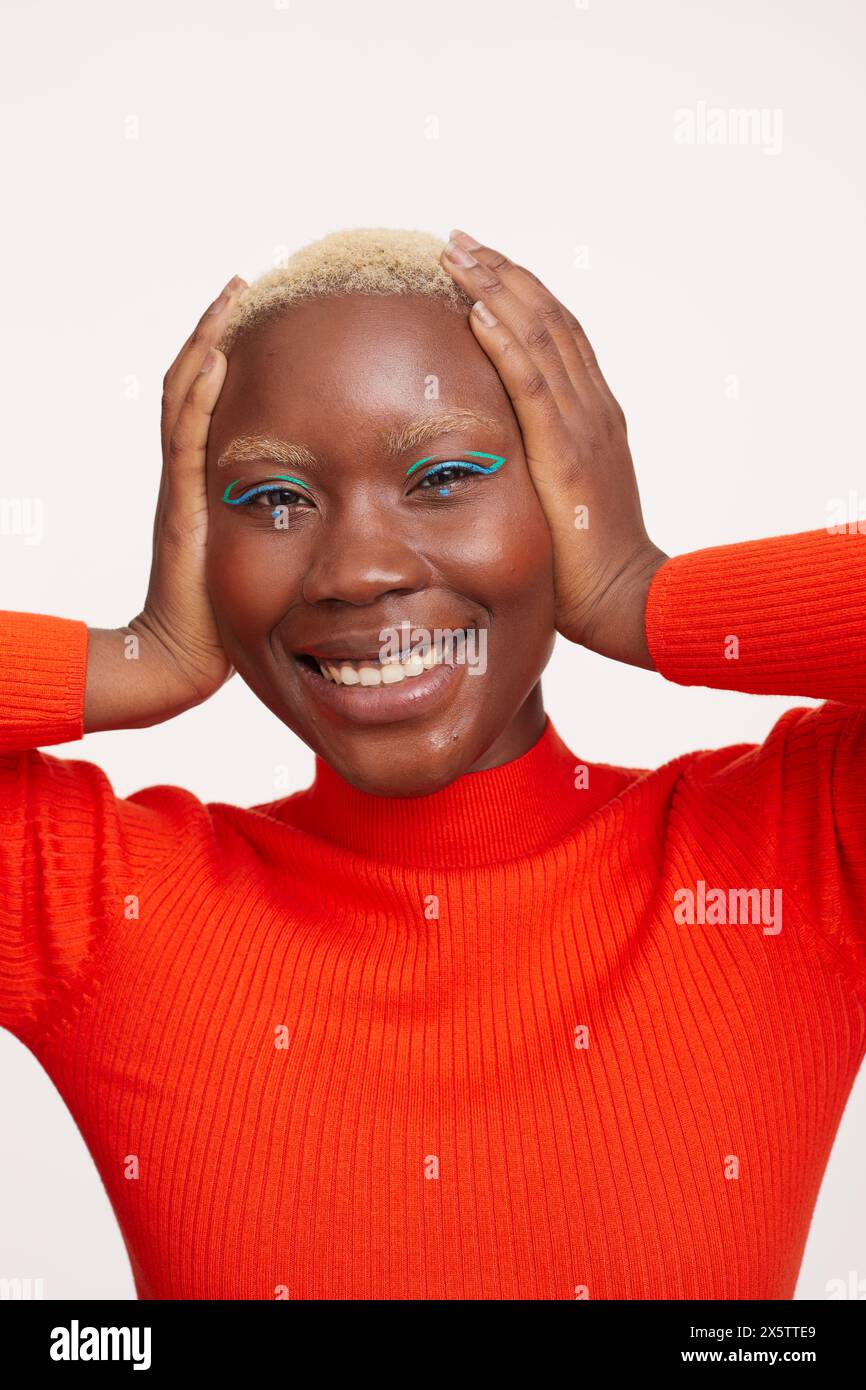 Portrait de femme souriante avec les cheveux blancs courts, tenant la tête dans les mains Banque D'Images